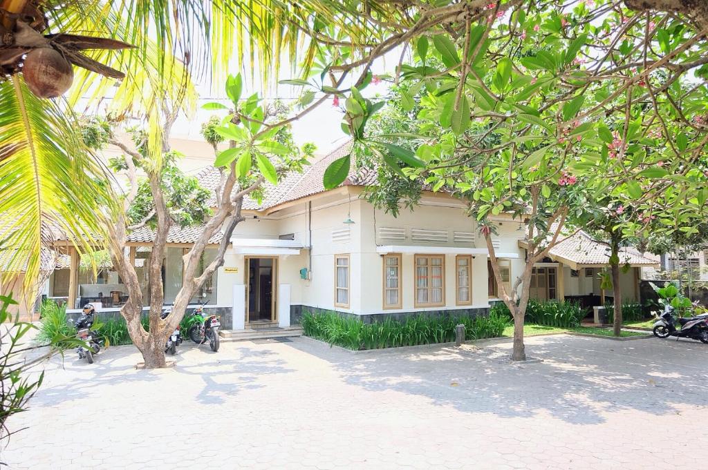 a white house with trees in front of it at Ndalem Suratin Guesthouse in Yogyakarta