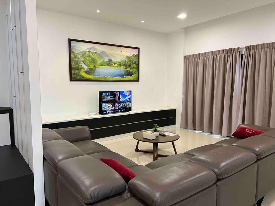 a living room with a leather couch and a table at Jk CozyStay 10Pax 300Mbps 3BedR 2BathR 2ShadedCarpark in Kuching
