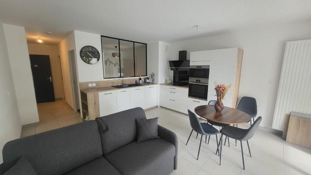 un salon avec un canapé et une table avec des chaises dans l'établissement Le Majuscule, à Annecy