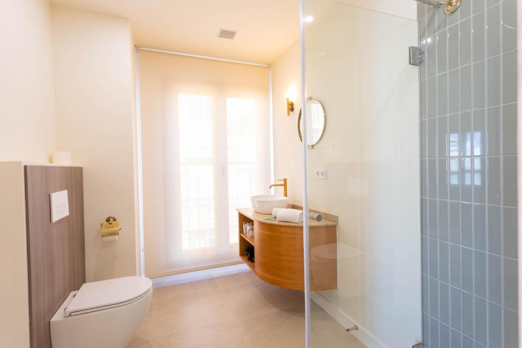 a bathroom with a toilet and a glass shower at Reina Victoria El Mercado in Alicante