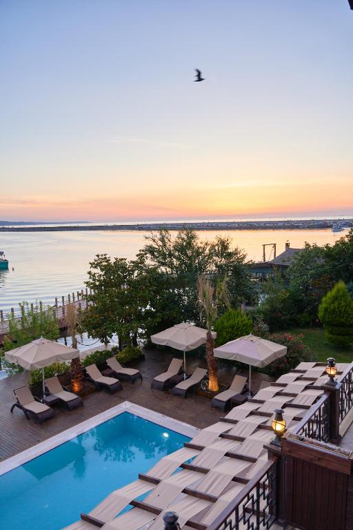 a swimming pool with chairs and umbrellas on a balcony at Phellos Suites Boutique Hotel in Şile