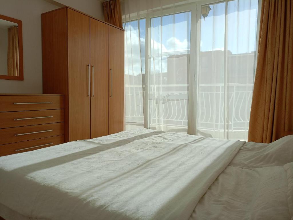 a bedroom with a large bed and a large window at CunninghamsSilver in Sunny Beach