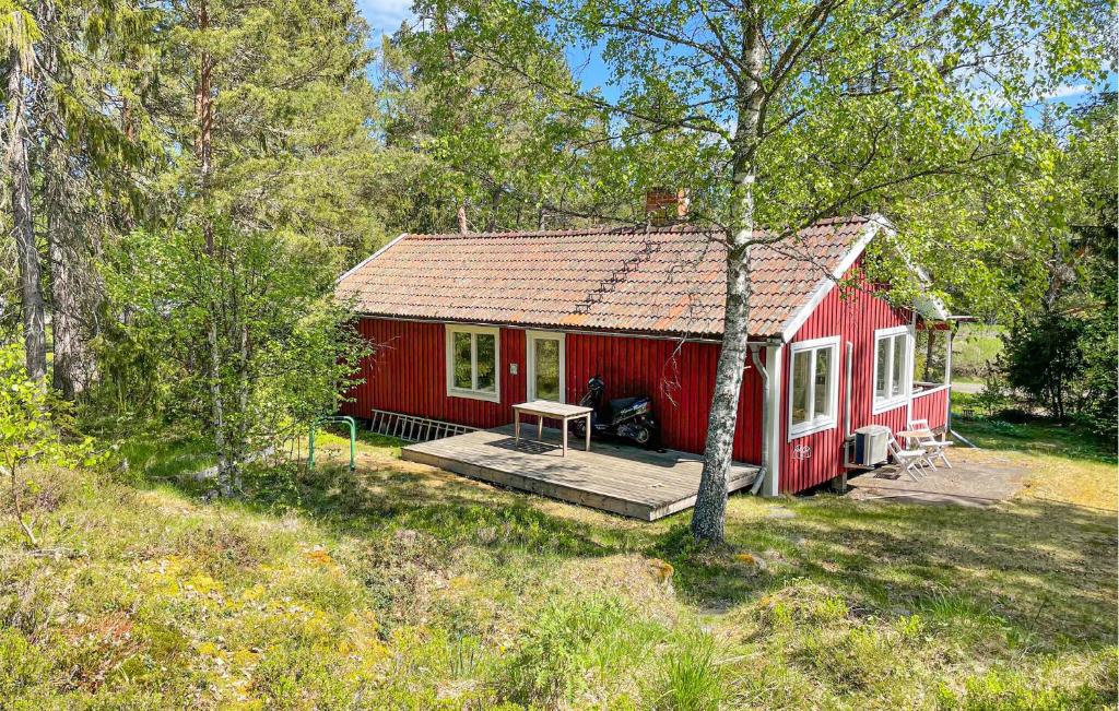 a red house with a wooden porch in the woods at 2 Bedroom Stunning Home In Gräddö in Gräddö