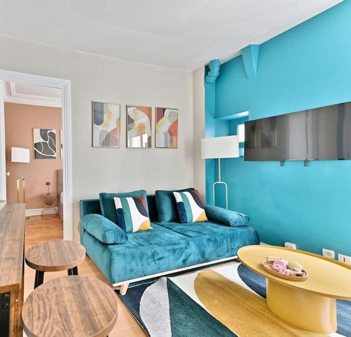 un salon avec un canapé bleu et une table dans l'établissement Appartement cosy et coloré au cœur de Paris, à Paris