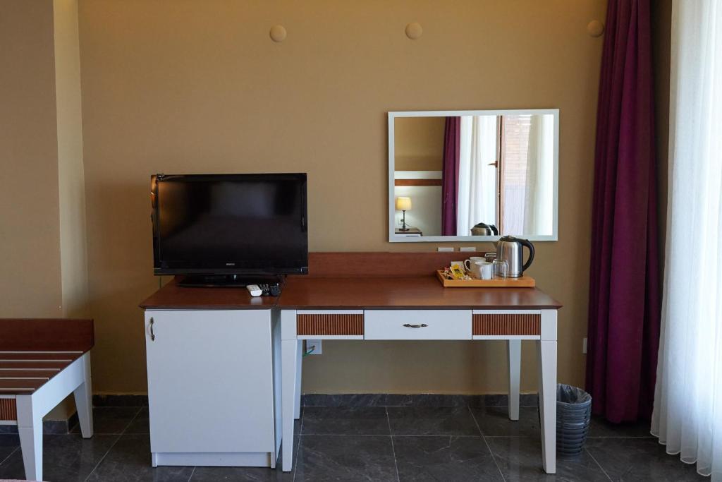 a desk with a television and a mirror in a room at Phellos Suites Boutique Hotel in Şile