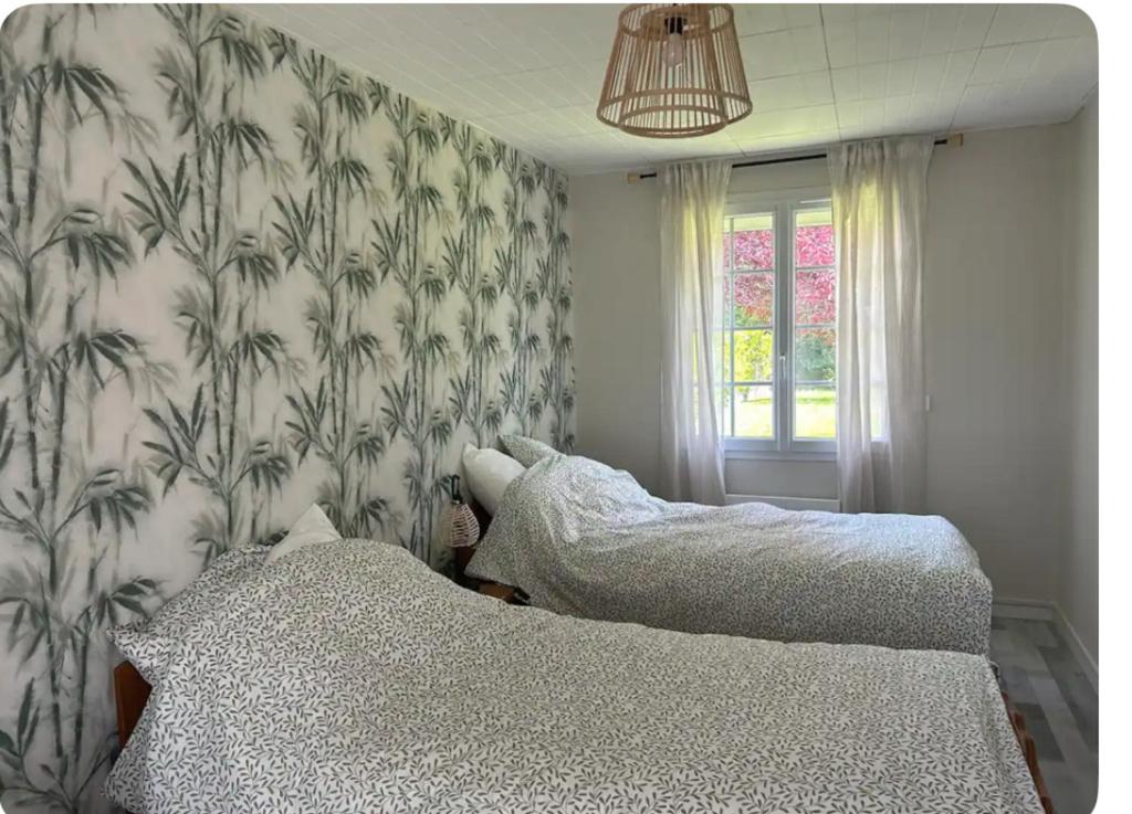 a bedroom with two beds and a wall with wallpaper at Enosis in Port-en-Bessin-Huppain