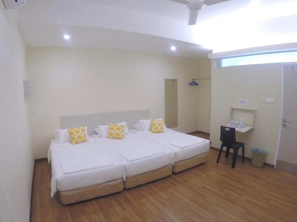 - une chambre avec un grand lit blanc et des oreillers jaunes dans l'établissement 1ACS Residence, à Kuching