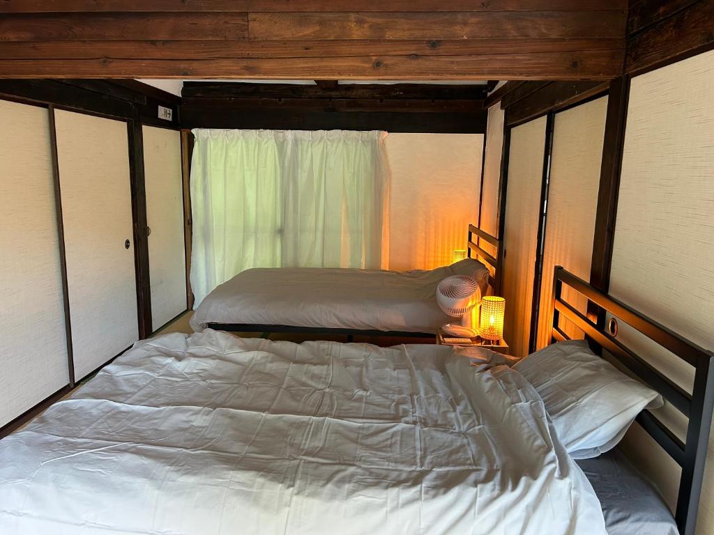 a bedroom with two beds and a window at 花子のいえ in Amidaji