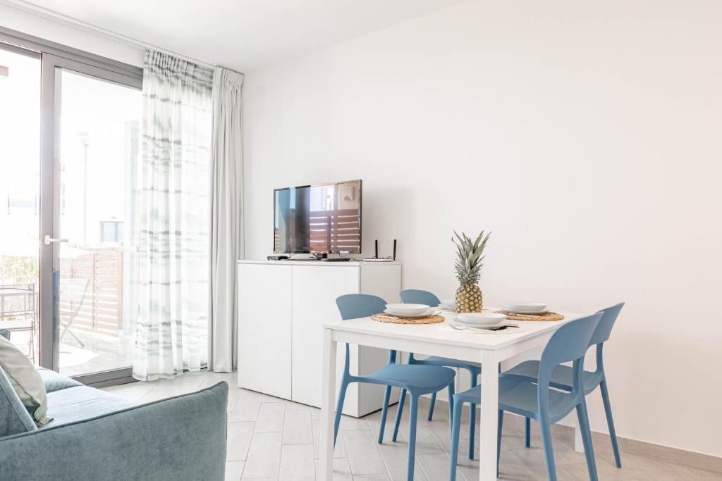 a dining room with a white table and blue chairs at H11 LUXURY 3B - Porto - Piscina - Jacuzzi in Santo Stefano al Mare