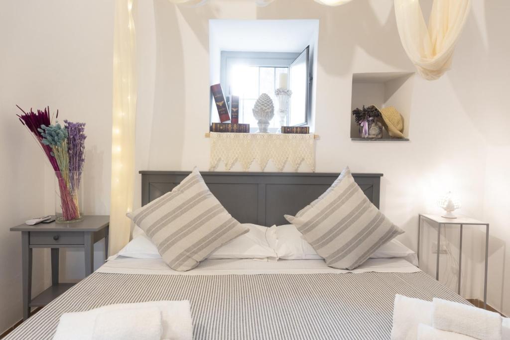 a bedroom with a bed with white pillows and a mirror at Trulli Arborea in Alberobello