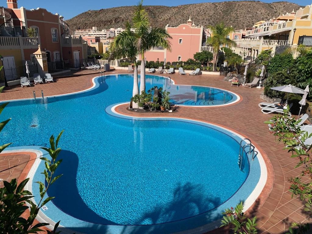 a swimming pool in a resort with palm trees and buildings at Paraiso Ocean Panorama in Palm-Mar