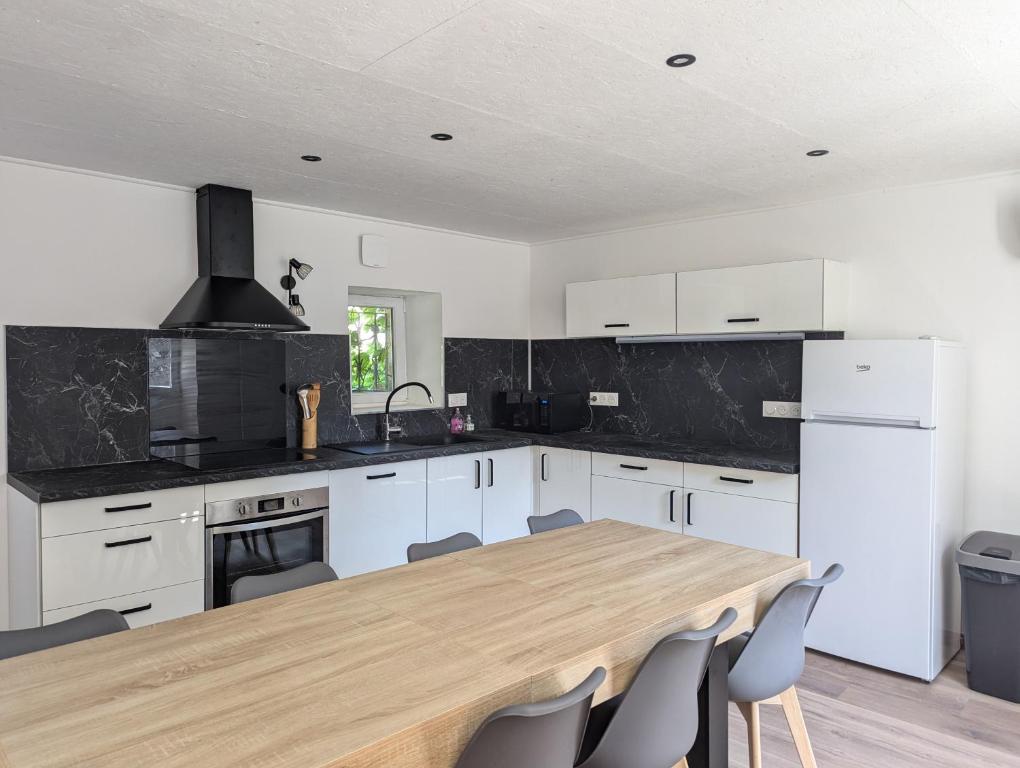 une cuisine avec des armoires blanches et une table en bois dans l'établissement Maison de village au centre de Vallon-Pont-d'Arc, à Vallon-Pont-dʼArc