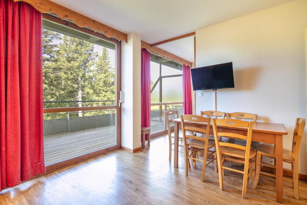 une salle à manger avec une table et une grande fenêtre dans l'établissement Le Chamroussien - Appt 6p, au pied des pistes, à Chamrousse