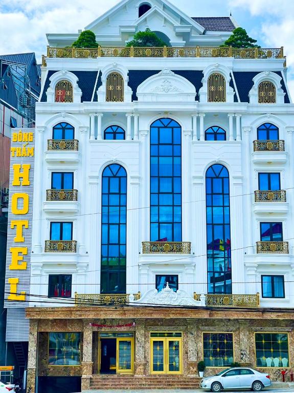a white building with windows and a car parked in front at Đông Thắm Hotel in Diện Biên Phủ