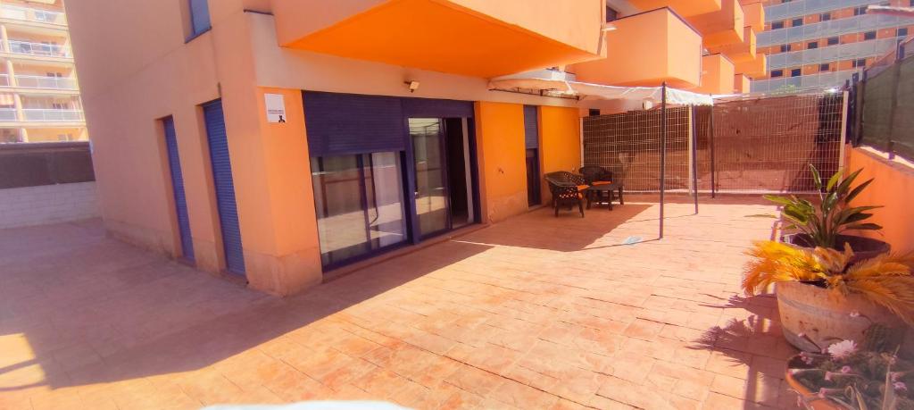 einen Außenblick auf ein Gebäude mit einer Terrasse in der Unterkunft Piso planta baja y gran patio con piscina comunitaria de alquiler temporal in Daimús