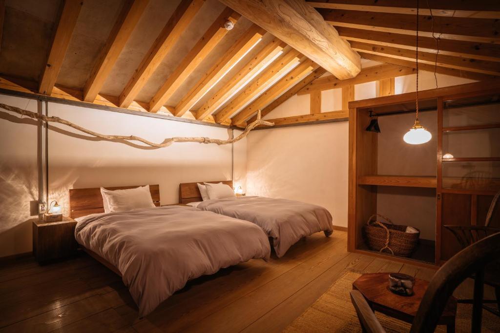 una camera con due letti in una stanza con soffitti in legno di Bed and Craft a Nanto