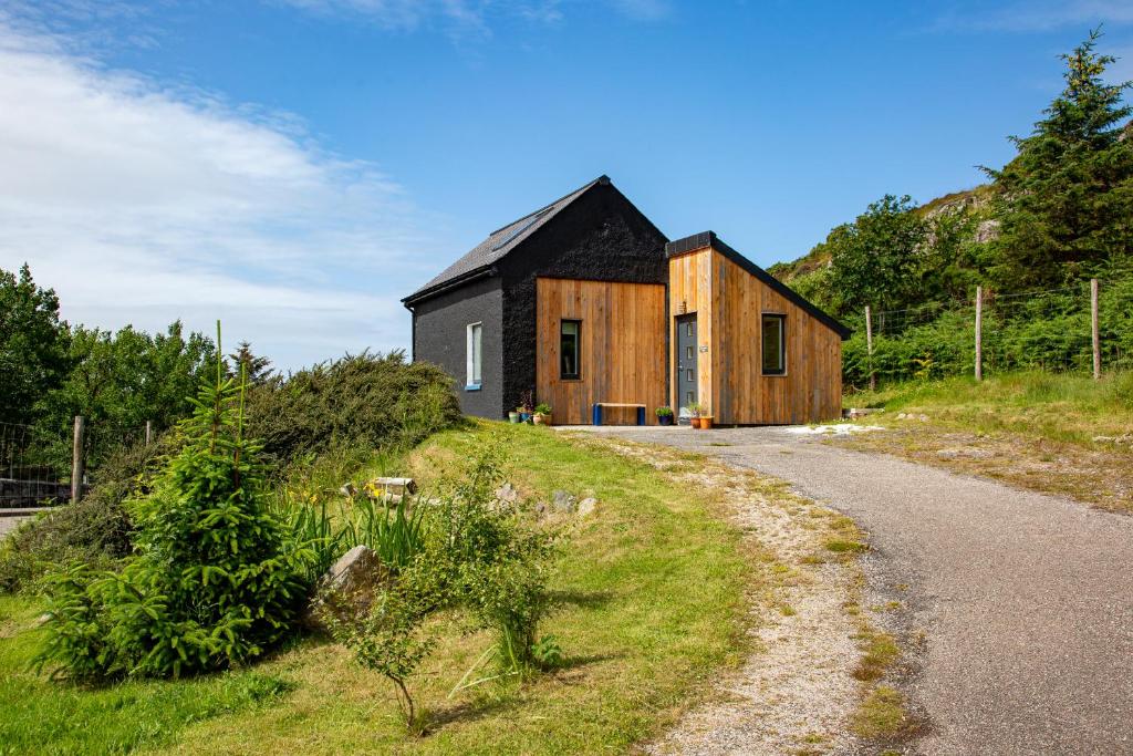 una piccola casa su una collina con una strada di The Old Coastguard Station, Lochinver a Lochinver