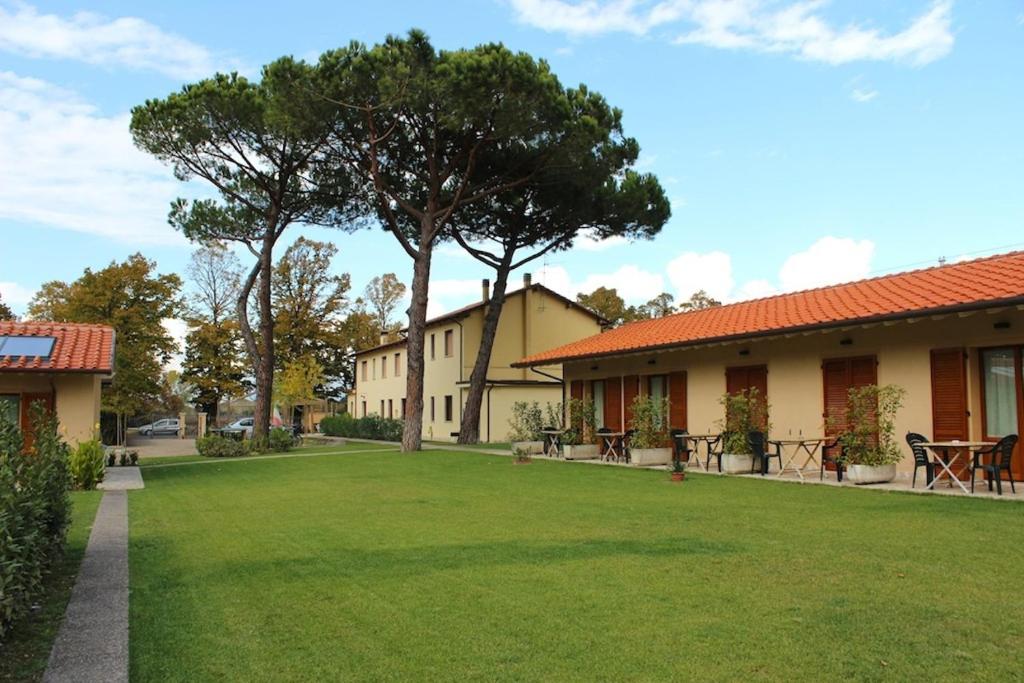 ein grüner Hof neben einem Gebäude mit einem Baum in der Unterkunft Villa Rosy in Torre del Lago Puccini