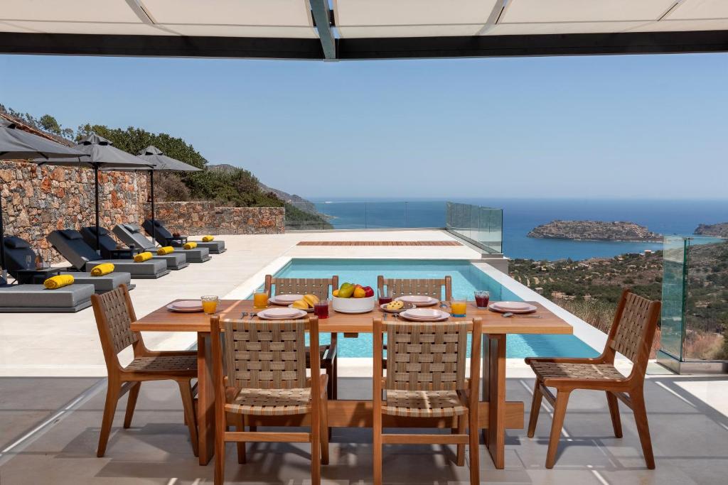 a dining room with a table and chairs and a pool at Villa Cristina in Elounda
