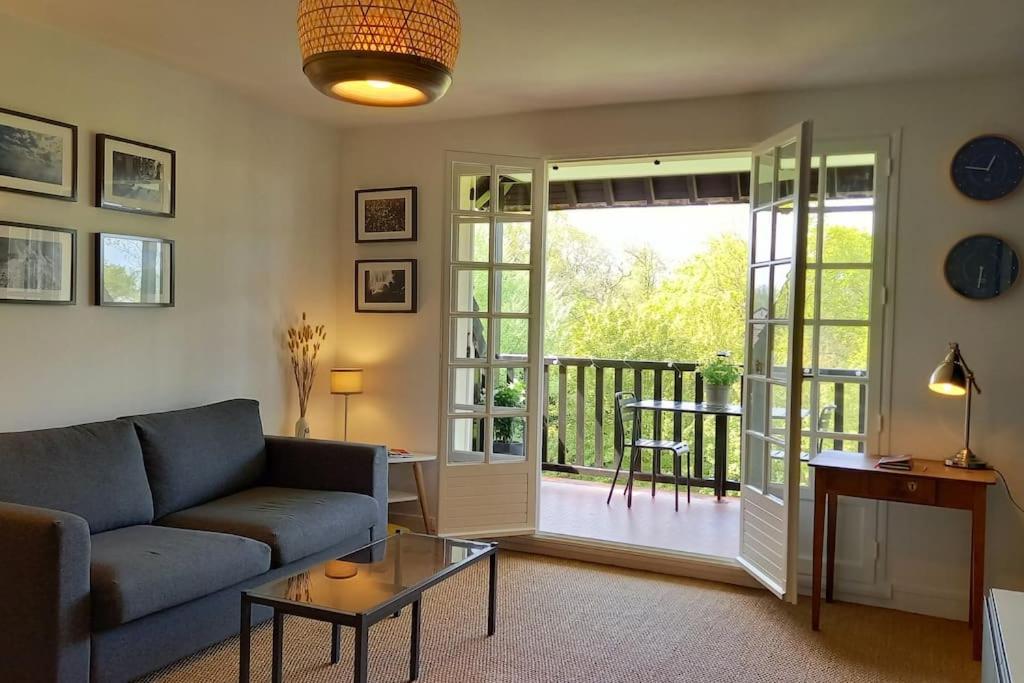 un salon avec un canapé et une table en verre dans l'établissement La Parenthèse Normande, à Villers-sur-Mer