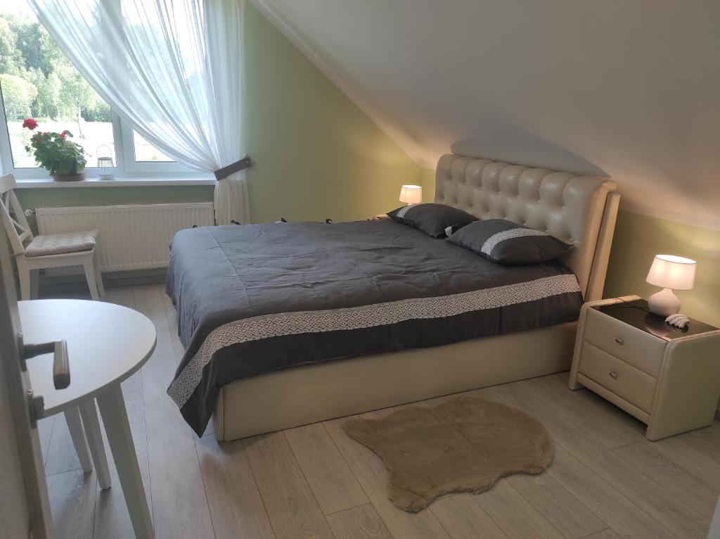 a bedroom with a bed and a table and a window at Viesu nams Sampale in Ķeipene