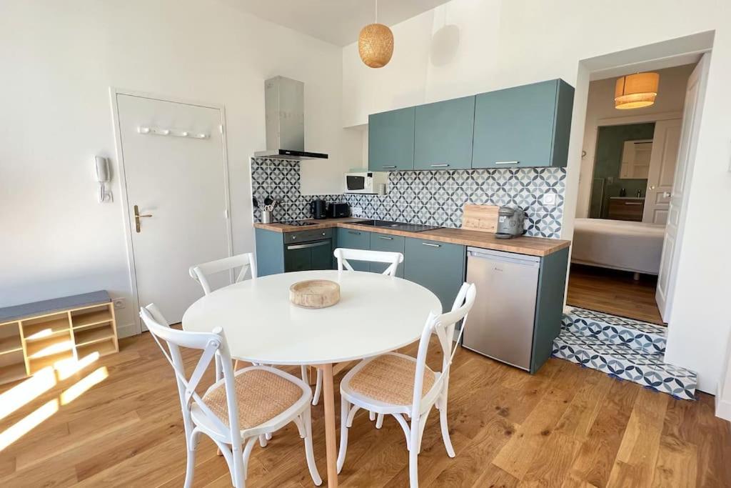 - une cuisine avec une table et des chaises blanches dans la chambre dans l'établissement La Corderie - Appartement sur le Quai aux Vivres, à Rochefort