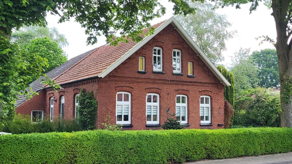 a red brick house with white windows and bushes at Ferienwohnung Emma s Fehnhaus, 55183 in Stickhausen
