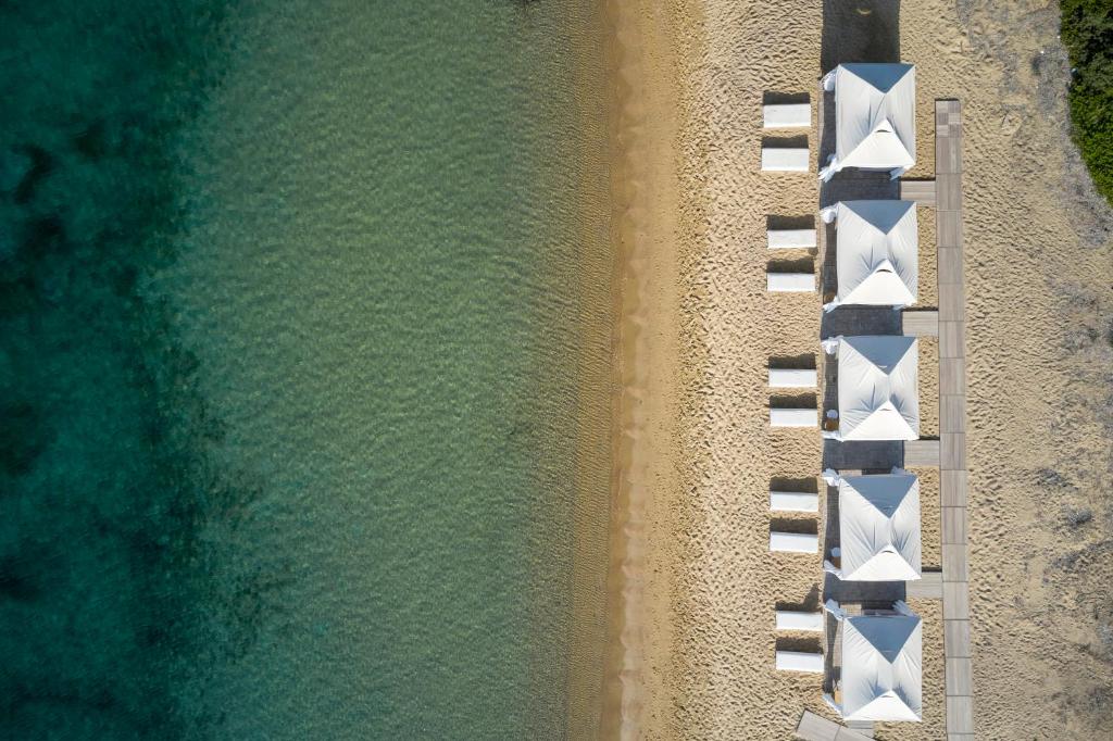 - une vue sur la plage avec une rangée de chaises blanches dans l'établissement Princess Resort, Santikos Collection, à Agia Paraskevi