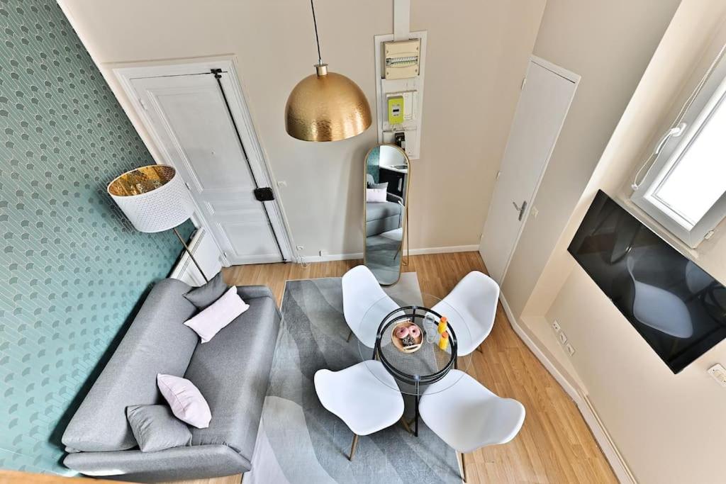 - un salon avec un canapé gris et des fauteuils blancs dans l'établissement Loft Mezzanine central à Paris 14ème, à Paris