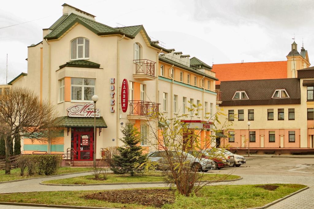 un edificio con una puerta roja en un aparcamiento en Slavia Hotel, en Grodno