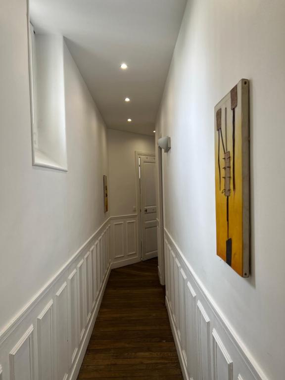 - un couloir d'une maison dotée de murs blancs et de parquet dans l'établissement Appartement Boulogne Rolland-Garros, à Boulogne-Billancourt
