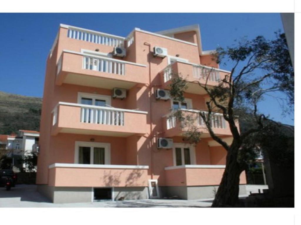 a pink building with a tree in front of it at Beautiful Loft in Petrovac na Moru