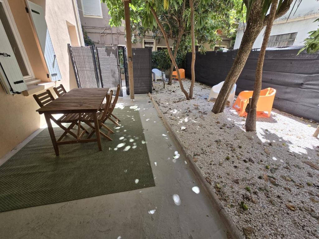 un patio avec une table, des chaises et des arbres dans l'établissement Gregbnb - T2 37m2 - Terrasse - Clim - Ouest - 3, à Toulon