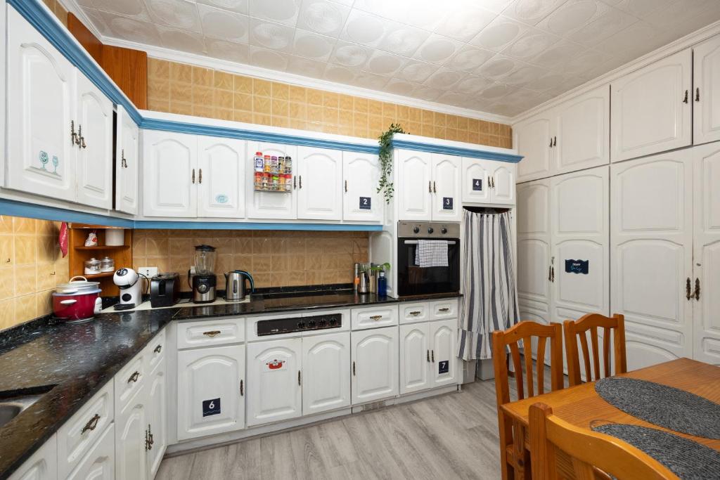 a white kitchen with white cabinets and a table at Kite & Surf Nomad House in Las Palmas de Gran Canaria