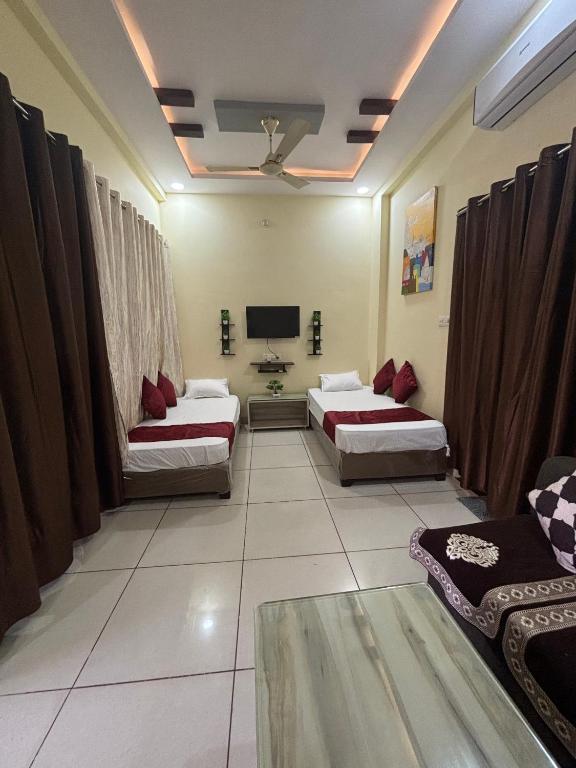 a room with two beds and a flat screen tv at Dream Ashoka Homestay in Ujjain