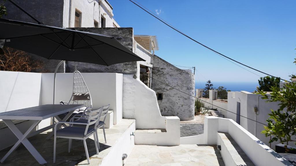 a patio with a table and chairs and an umbrella at The Fig Tinos in Triandáros