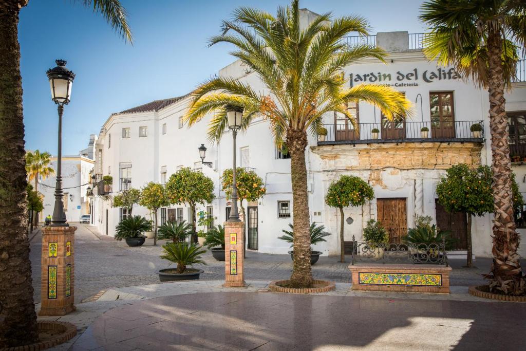 a street with palm trees in front of a building at Hotel La Casa del Califa in Vejer de la Frontera