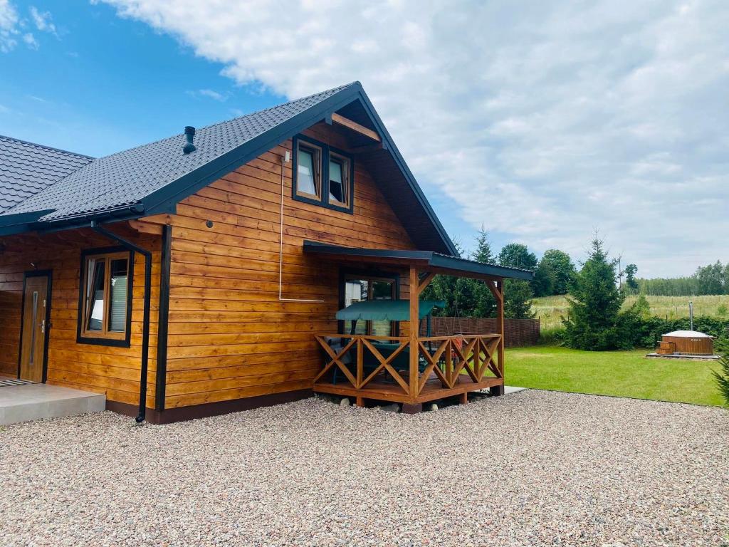 a wooden cabin with a porch and a deck at Dom Wakacyjny Bogaczewo in Bogaczewo