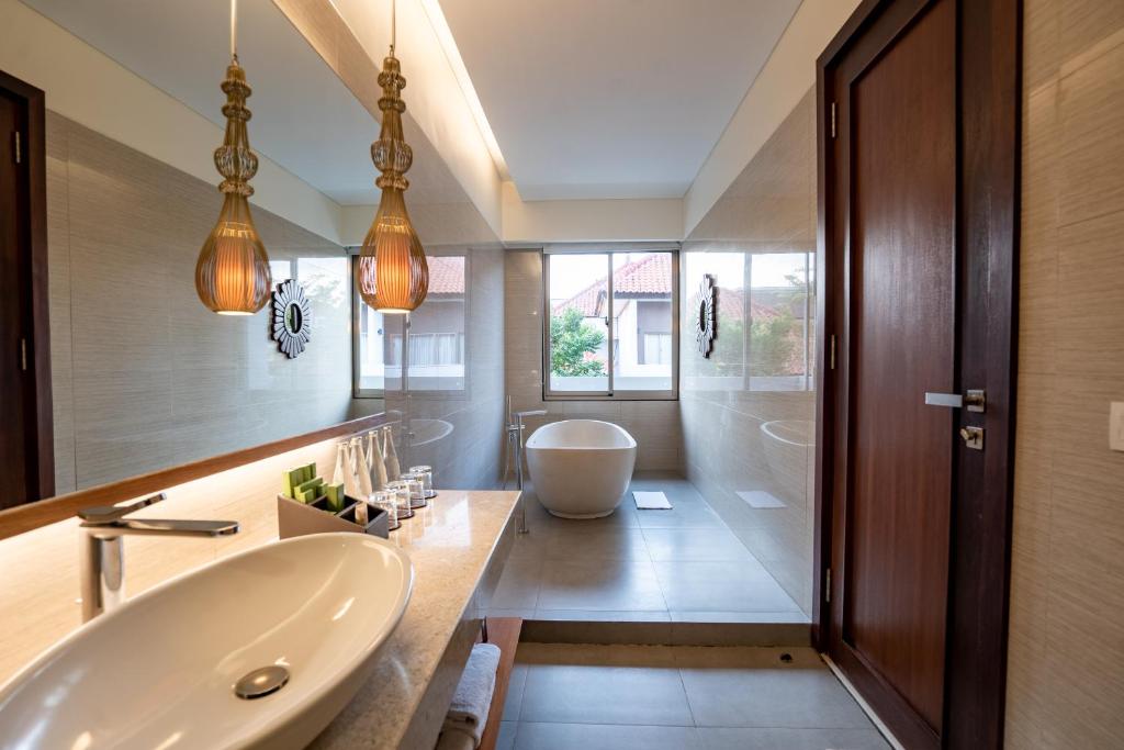 a bathroom with a sink and a bath tub at MERUSAKA Nusa Dua in Nusa Dua
