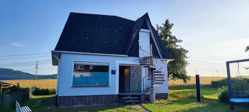 una pequeña casa blanca con techo negro en Ferienwohnung Am Dingel, en Hofgeismar