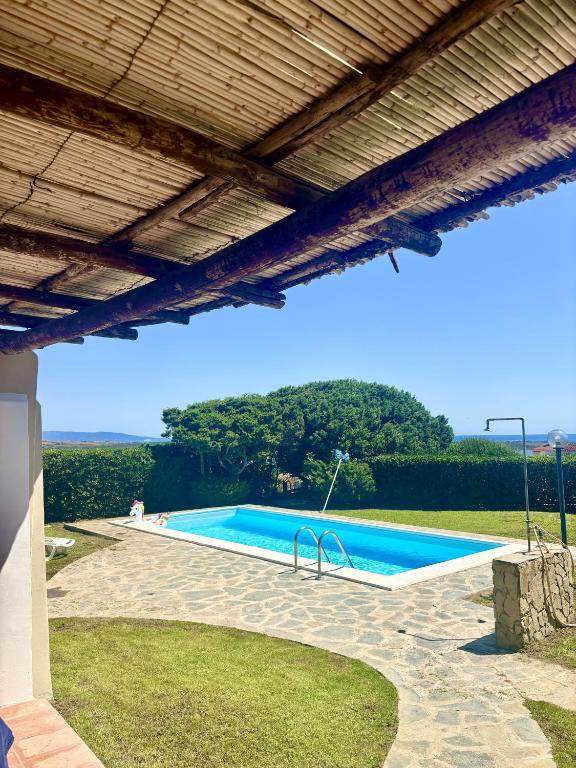 a swimming pool under a wooden roof at Villa del Tramonto - Piscina privata in Stintino