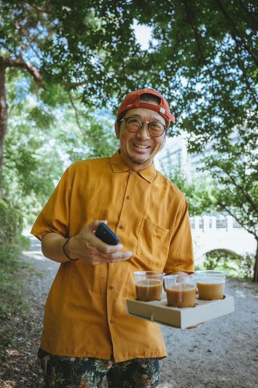 松山市にある麦宿 伝 Guest House Brewの食べ物の入った皿と食べ物の入ったトレイを持っている男性