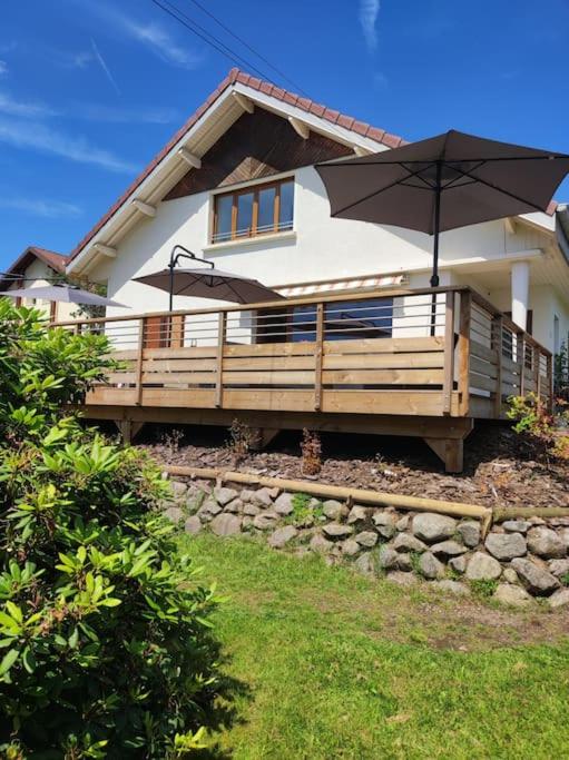 une maison avec un parapluie devant dans l'établissement Gîte Papillon 6 à14 personnes - Jacuzzi, à Gérardmer