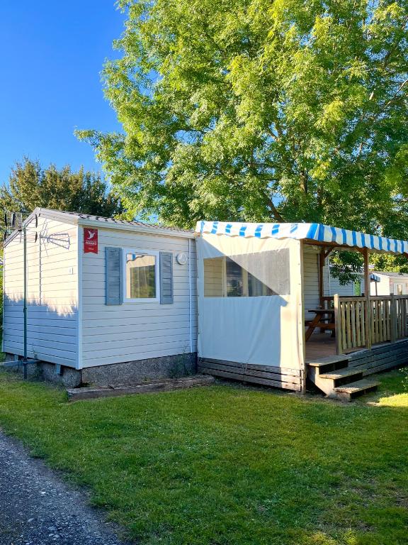 un hangar blanc avec une terrasse couverte et une terrasse dans l'établissement Camping la Faloise - Mobil-home 2 chambres, à Angicourt