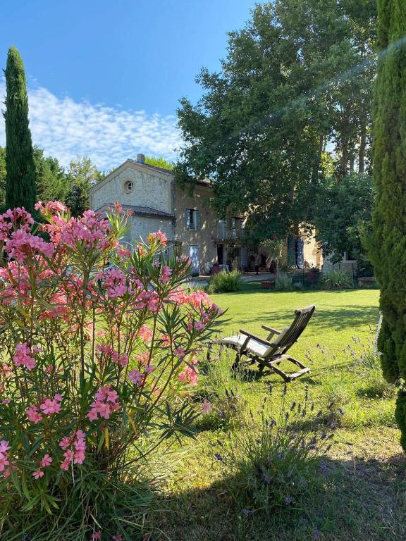 un banc dans une cour avec des fleurs et une maison dans l'établissement Maison d'hôtes, superbe et spacieuse ,dans un cadre charmant calme et verdoyant, à Pernes-les-Fontaines