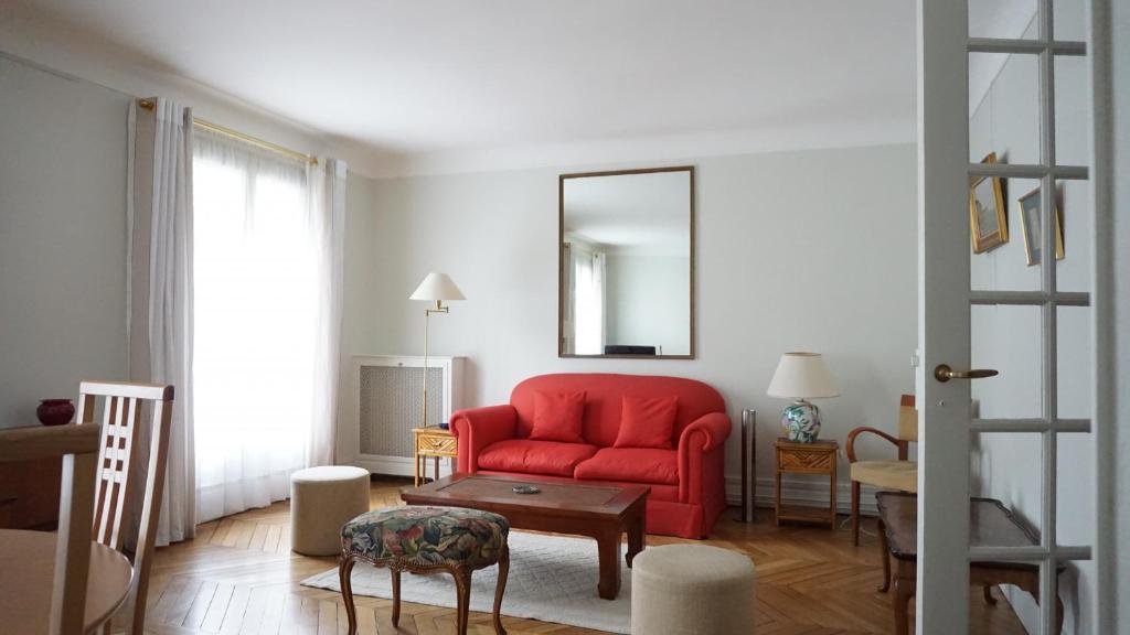 un salon avec un canapé rouge et un miroir dans l'établissement Rue Yvon Villarceau - Paris 16, à Paris