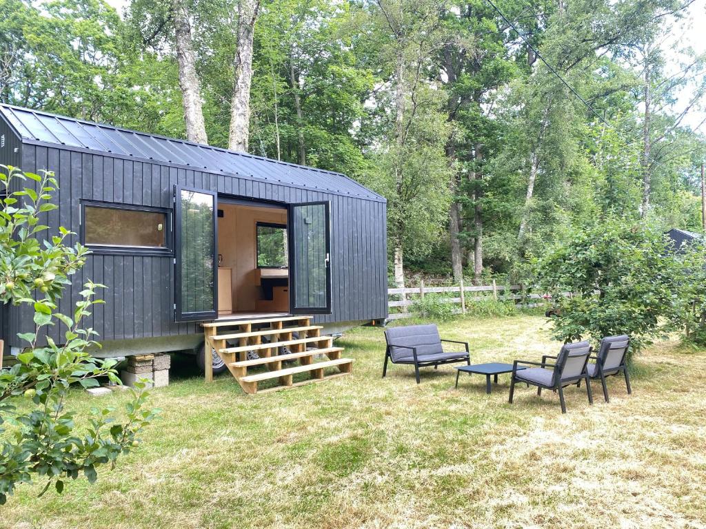 a black tiny house with chairs and a table at Elevated Tiny House Glamping in Tjøme