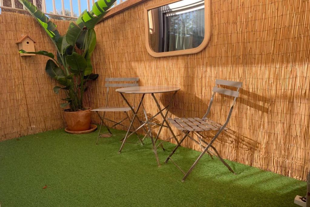 une table, deux chaises et une plante en pot dans l'établissement Au cœur des vacances, à Bandol