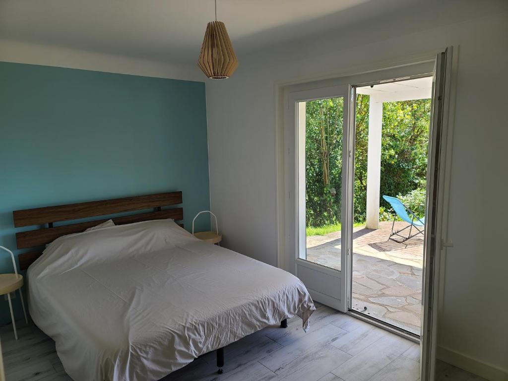 a bedroom with a bed and a sliding glass door at Socoa : appartement calme à 200m de la plage in Ciboure