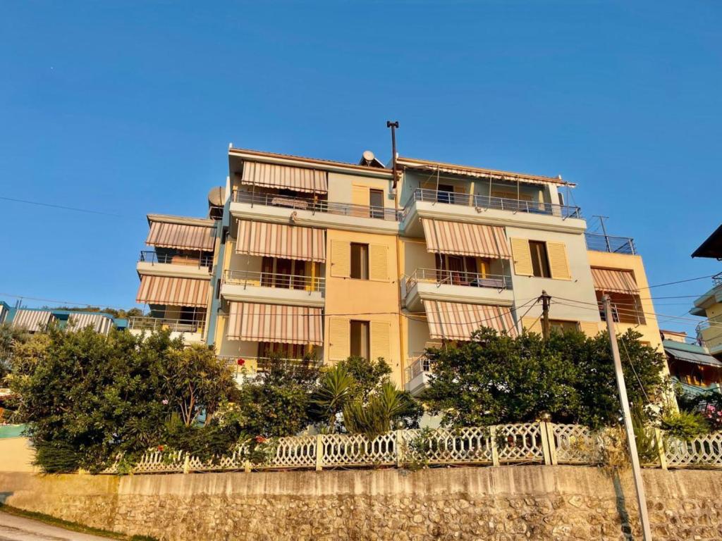 a yellow building with a fence in front of it at Onis Sea View Apartments in Orikum